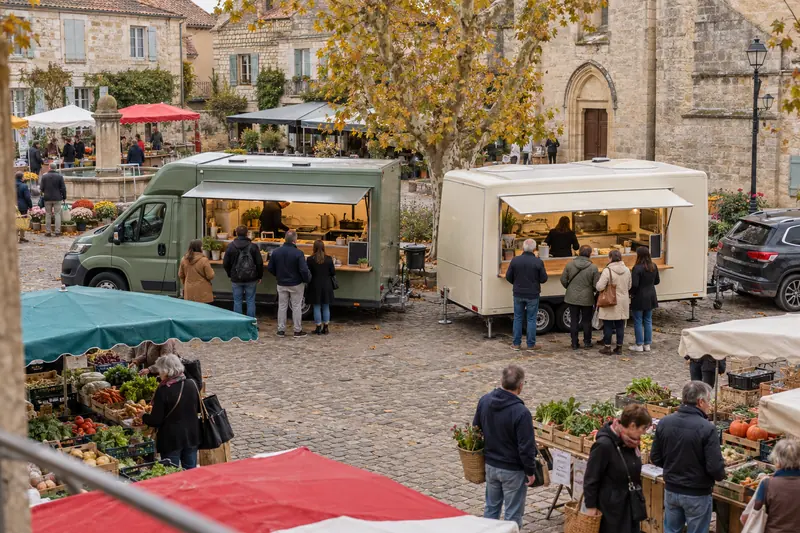 Un camion food truck et une remorque food truck côte à côte sur la place du marché d’une petite ville française